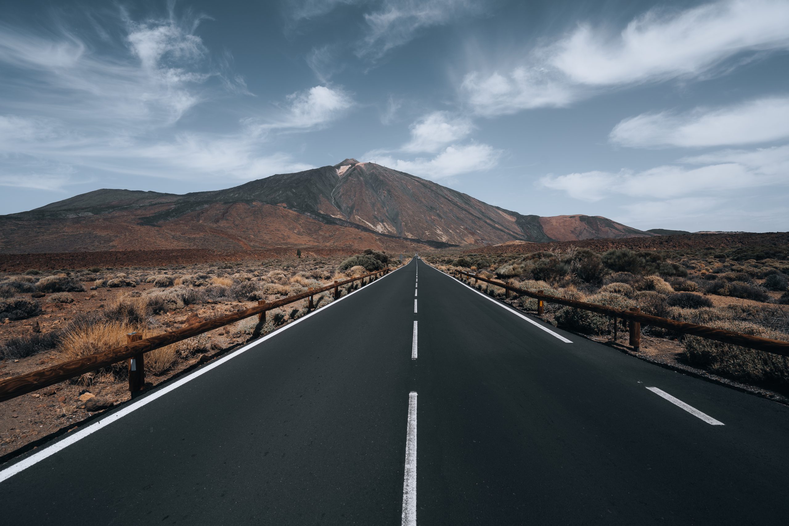 Toma en ángulo alto de una carretera rodeada de colinas bajo el cielo nublado