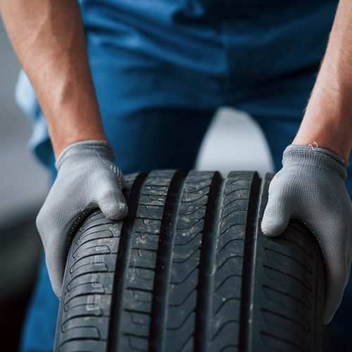 Dirt on the wheel. Mechanic holding a tire at the repair garage. Replacement of winter and summer tires Dirt on the wheel. Mechanic holding a tire at the repair garage. Replacement of winter and summer tires.